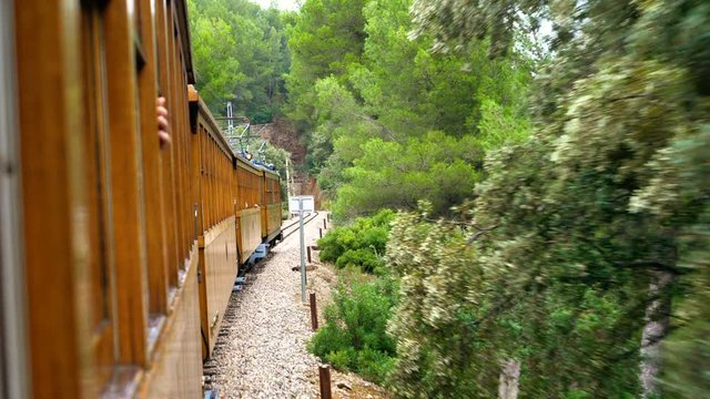 Young happy woman enjoys ride with old wooden train through beautiful mountain landscape nature in 4k