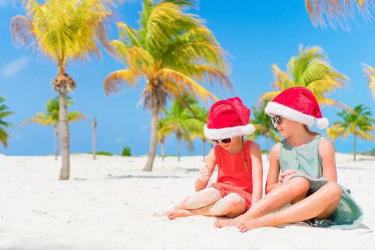 Adorable little kids have fun in Santa hat during Christmas beach vacation. New Year on the beach