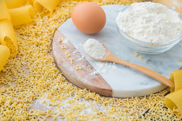 Uncooked raw pasta alphabet yellow letters with macaroni and lasagna