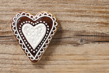Gingerbread cookie in heart shape on wood