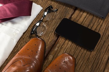 Shoes, spectacle and mobile phone on wooden plank