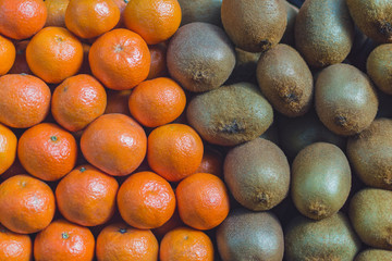 background texture of folded kiwi fruits and tangerines on the market counter