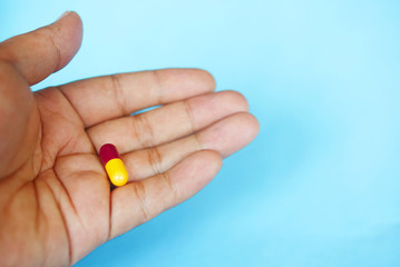 Hand Holding Capsule Over Blue Background
