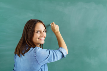 lehrerin schreibt an die tafel und schaut über die schulter zurück