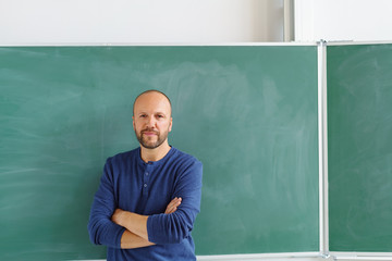 lehrer steht mit verschränkten armen vor der leeren schultafel