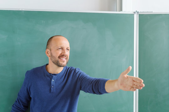motivierter lehrer zeigt mit der hand nach vorne in die klasse