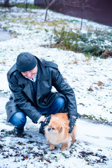 Fototapeta na wymiar Senior man Walking Dog Through Snowy Street. Mature Man enjoys a winter morning in yard. His pet frolic in the snow at his feet.