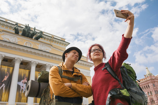 Young couple of tourists taking selfies against the Bolshoi theatre in Saint-Petersburg