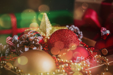 Composition with gift and Christmas decorations in golden box on black background toned bokeh