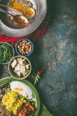 Indian cuisine meals in bowls with spices on dark rustic background, top view, copy space