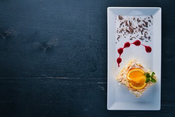 Layered cake with orange flavor. On a wooden background. Free space for your text. Top view.