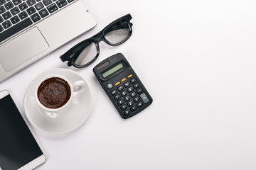 White Office Desk. Laptop, phone, cup of coffee, glasses, pen, pencil. On a white background. Top view. Free space for text.