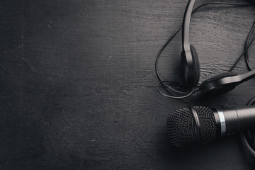 Headphones and microphone on a wooden black table. Studio. Top view. Free space for text. Copy...
