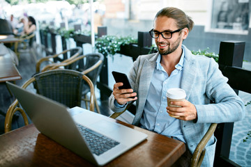 Man With Phone Drinking Coffee In Cafe
