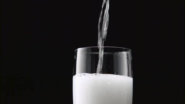 Champagne poured into glass. Black background. Close up