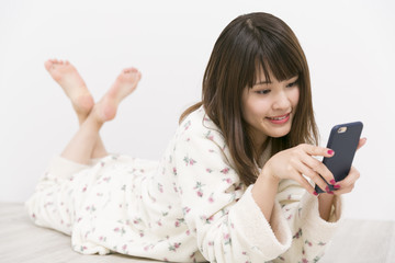 Fototapeta premium パジャマで携帯電話を使う女性