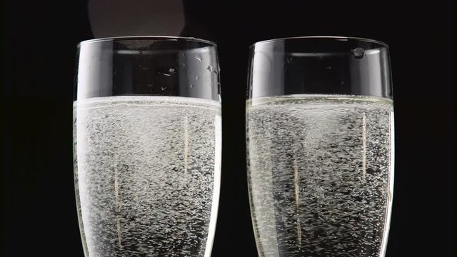 Two flutes of chilled sparkling wine. Bokeh blinking black background. Close up
