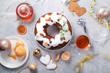 Traditional christmas cake with dried fruits soaked in rum and sugar glaze. Teatime with heart-shaped ginger cookies. Christmas background with tangerines and festive decoration.