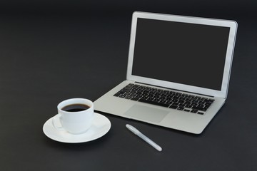 Obraz na płótnie Canvas Cup of coffee, laptop and pen on black background