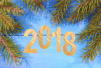 2018 wooden number on Christmas holiday background. Figures with fir branches on a blue wooden background. 3D illustration