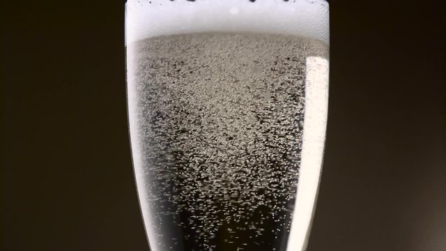 Bubbles of champagne are intensely circling in a glass. Close up