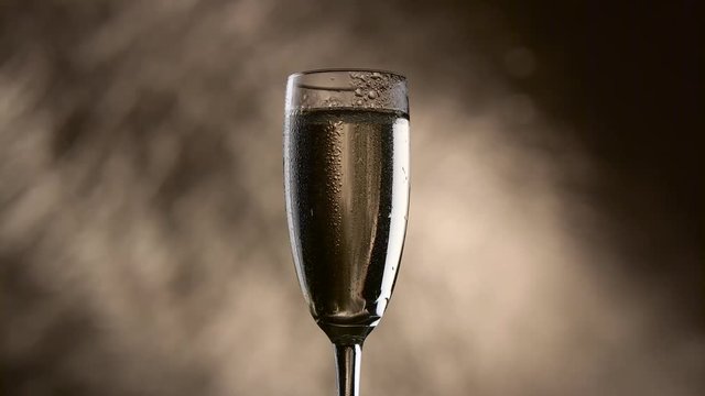 Drop drips down the wall of a glass with champagne on a bokeh background