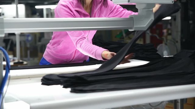 The woman-the inspector checks the quality of products on production line of hosiery. She makes a note in the electronic journal