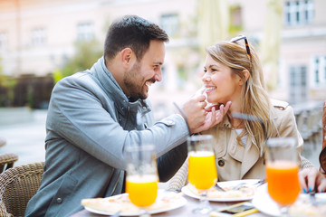Couple eating pizza snack outdoors and smiling