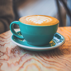 blue mug of cappuccino with milk foam on a wooden table square image