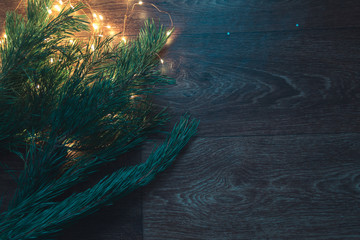 Christmas tree branches with Christmas decorations on a wooden background.
