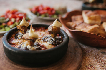Dish with mushrooms and white sauce in bowl on wooden stand. Traditional Turkish food. Very tasty dish of national cuisine.