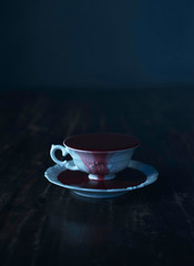 Fototapeta premium White tea cup in dark blood on wooden table.