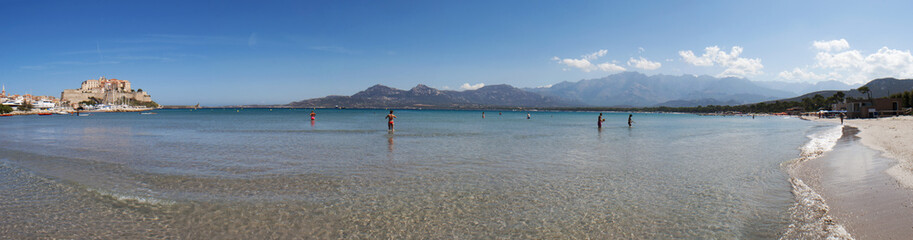 Corsica, 03/09/2017: il Mar Mediterraneo e la spiaggia con vista sullo skyline dell'antica Cittadella di Calvi, con le sue antiche mura e le barche nel porto turistico