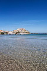 Corsica, 03/09/2017: il Mar Mediterraneo e la spiaggia con vista sullo skyline dell'antica Cittadella di Calvi, con le sue antiche mura e le barche nel porto turistico