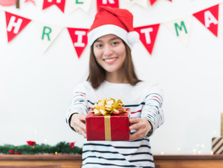 asia woman in xmas party gift giving red box to friend with smiling face in christmas party,Holiday celebration in winter season,selective focus on present.