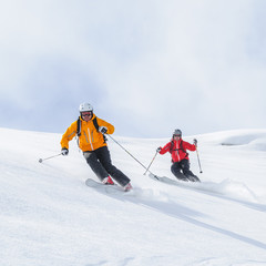 Zwei Skifahrer befahren gemeinsam einen steilen Hang