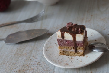 Gentle Muscovy cake with raspberry curd and poppy cakes, decorated with strawberries, chocolate, marshmallows and frosting on a light wooden background
