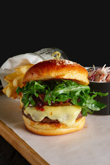 Juicy beef burger with lingonberry sauce, melted cheese, arugula served with fried potato and red cabbage