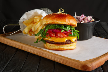 Juicy beef burger with lingonberry sauce, melted cheese, arugula served with fried potato and red cabbage