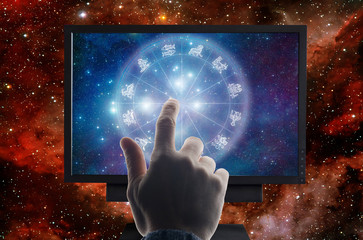 male hand touching computer monitor with zodiac signs horoscope like a concept astrology on-line,...