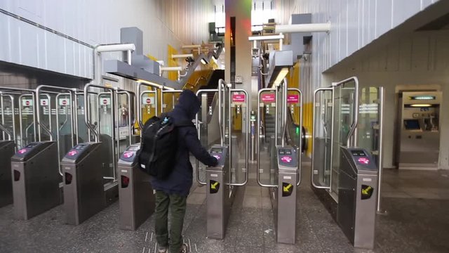 Back view on Man with a backpack passes through the turnstiles in the subway