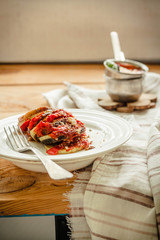 Warm vegetarian ratatouille made of eggplants, squash, tomatoes and onions. Served on a rustic background. Healthy vegetarian meal concept.
