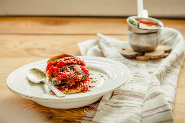 Warm vegetarian ratatouille made of eggplants, squash, tomatoes and onions. Served on a rustic background. Healthy vegetarian meal concept.
