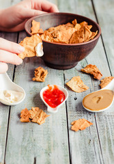 Close up of a female hands eating a delicious Mexican snack. Healthy chips a tortilla, nachos with organic classic sauce.