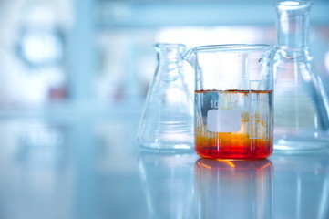 orange solution in beaker and flask in chemistry science laboratory background