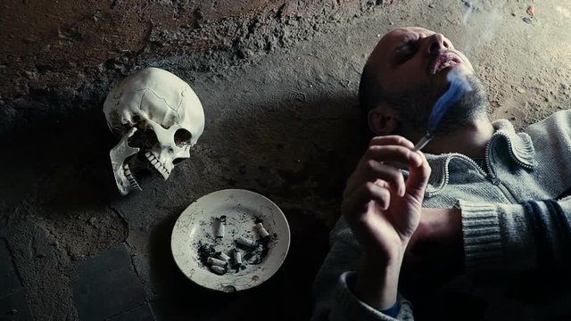 Smoking kills concept, portrait of a smoking man on a background of a skull