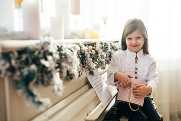 A cute girl sits at a white fortnpiano