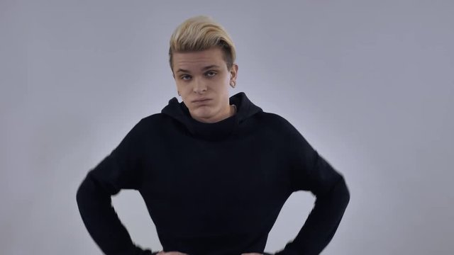 portrait millennial guy sighs heavily blonde hair wearing casual black hoodie posing in studio on background