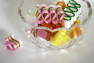 One broken piece of ribbon candy beside a bowl full.