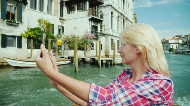 A young woman takes a picture of himself against the background of Venice, sailing by a water taxi on the Grand Canal. Accommodation in Italy